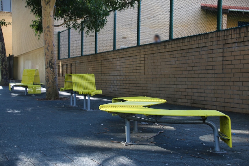 Bright yellow public seating, including individual chairs and a long curved bench.