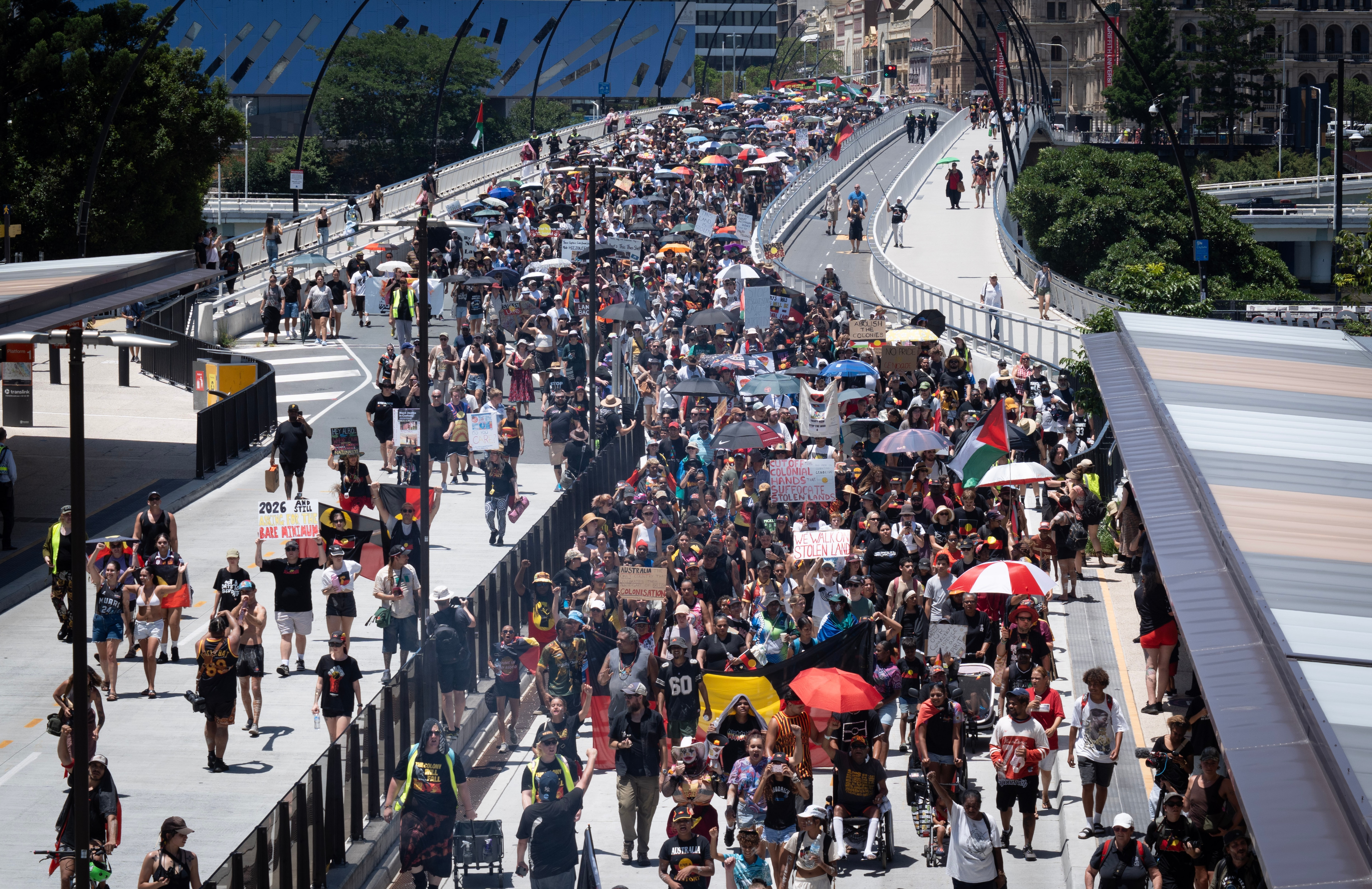 A view from above of a large crowd of people marching across Victoria Bridge in Brisbane.