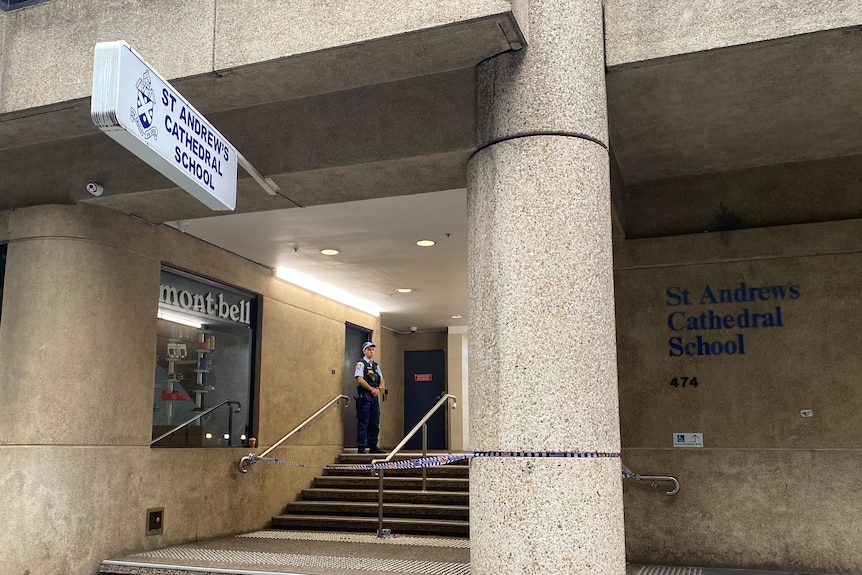 A police officer in uniform guards a door at St Andrews Cathedral School in the Sydney CBD