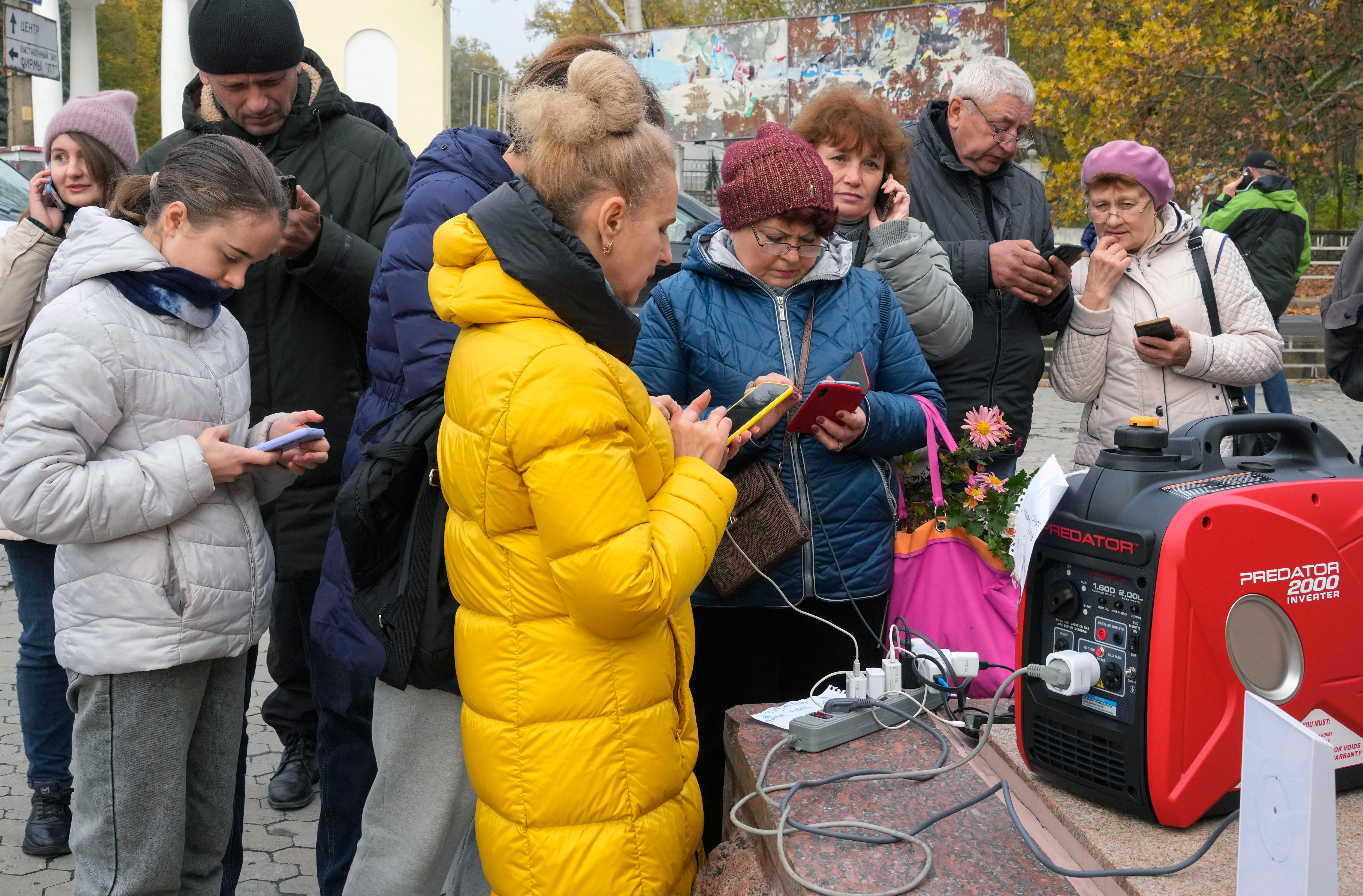 Several people stand around a power generator charging their phones