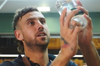 A close-up of a man looking at liquid in a jar