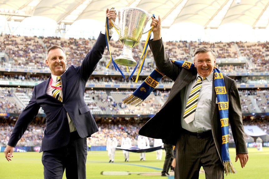 Two men hold the AFL Premiership trophy aloft