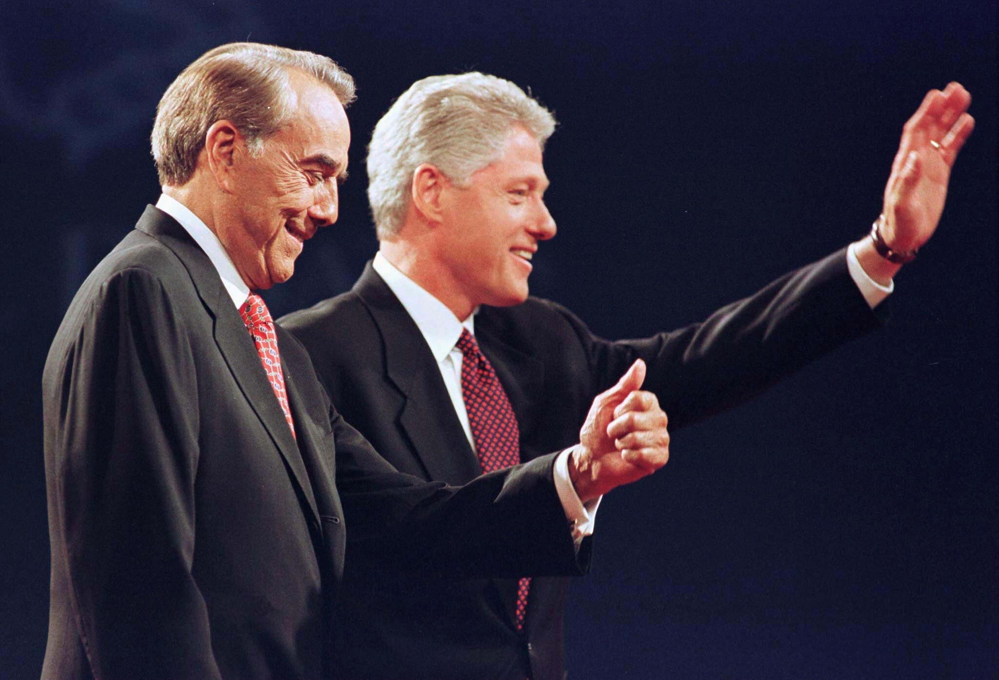 Bob Dole gives up the thumb while standing next to Bill Clinton.