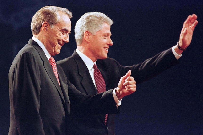 Bob Dole gives a thumbs up while standing next to Bill Clinton.