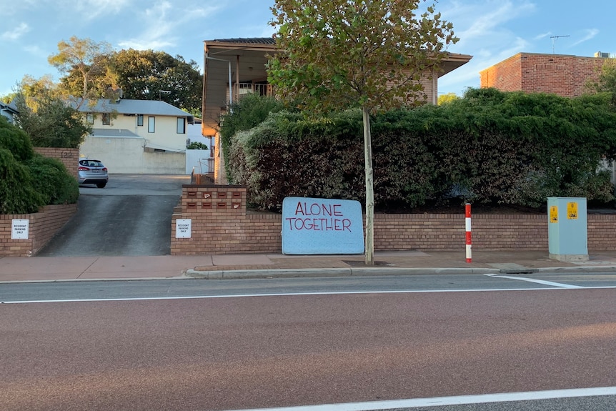 A mattress with Alone Together written on it on the side of the road