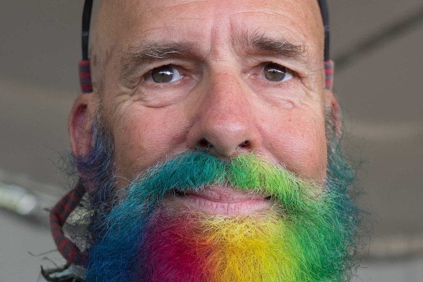 An older man with a rainbow-coloured beard