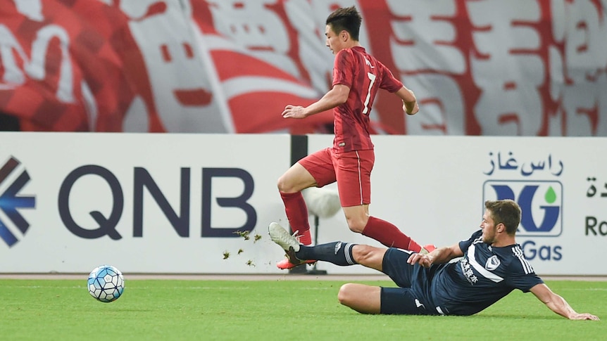 Shanghai SIPG's Wu Lei and Melbourne Victory's Matthieu Delpierre compete for the ball.