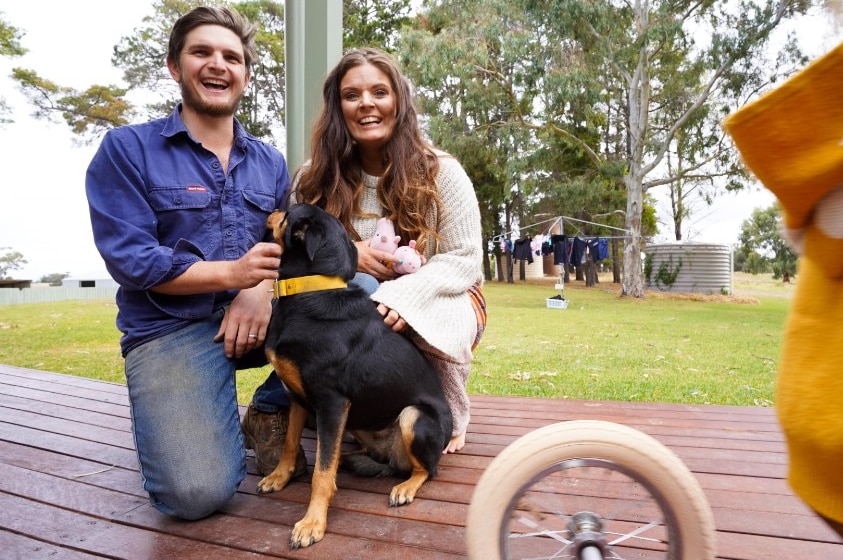 Lucy and Josh laugh with kelpie Josie on the back porch of their farm.