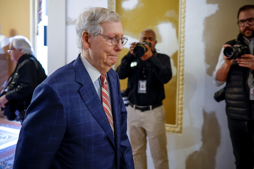 US Senate Minority Leader Mitch McConnell walking with his lips pursed. 