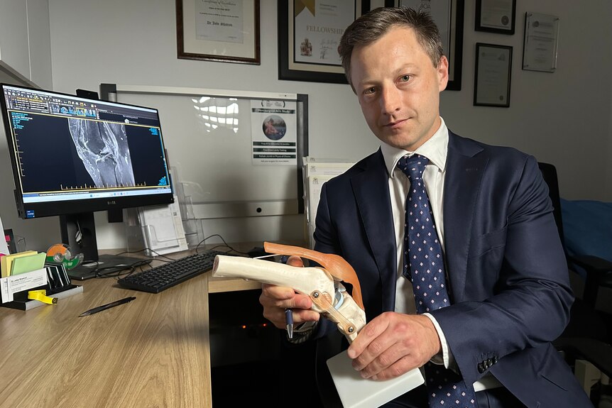Doctor Jobe Shatrov showing off a model of a knee. 