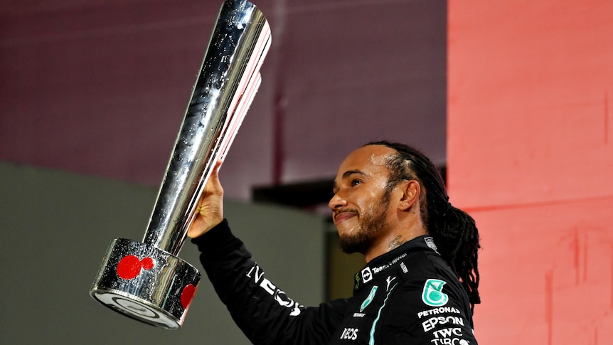 Race driver holds his winner's trophy.