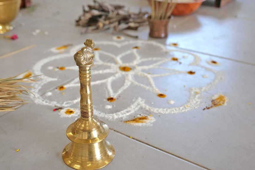 Bell standing next to a floral design on the temple floor.