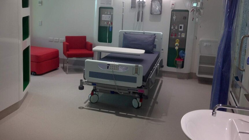 One of the rooms at the hospital with purple bedding and red chairs.