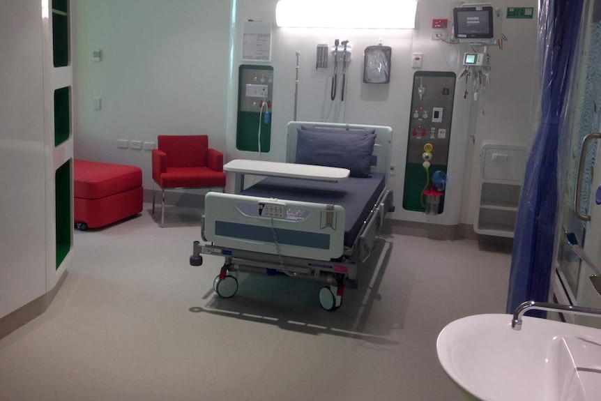 One of the rooms at the hospital with purple bedding and red chairs.