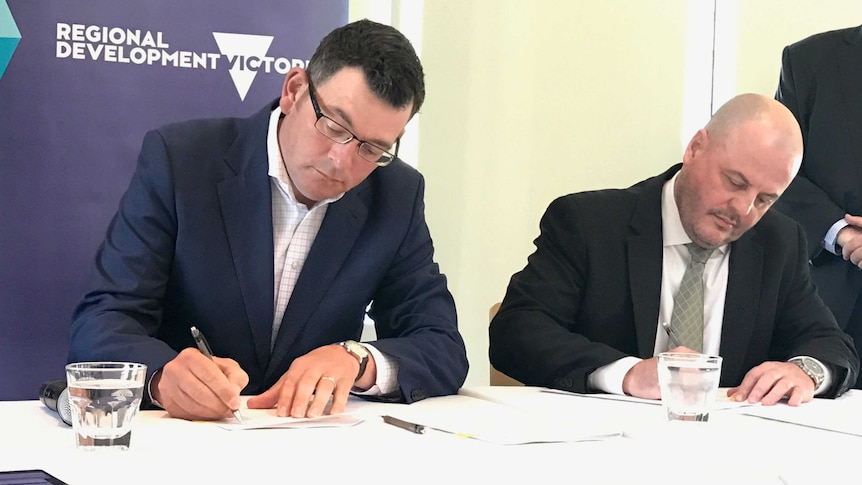 Victorian Premier Daniel Andrews and a Fujitsu representative sign paperwork