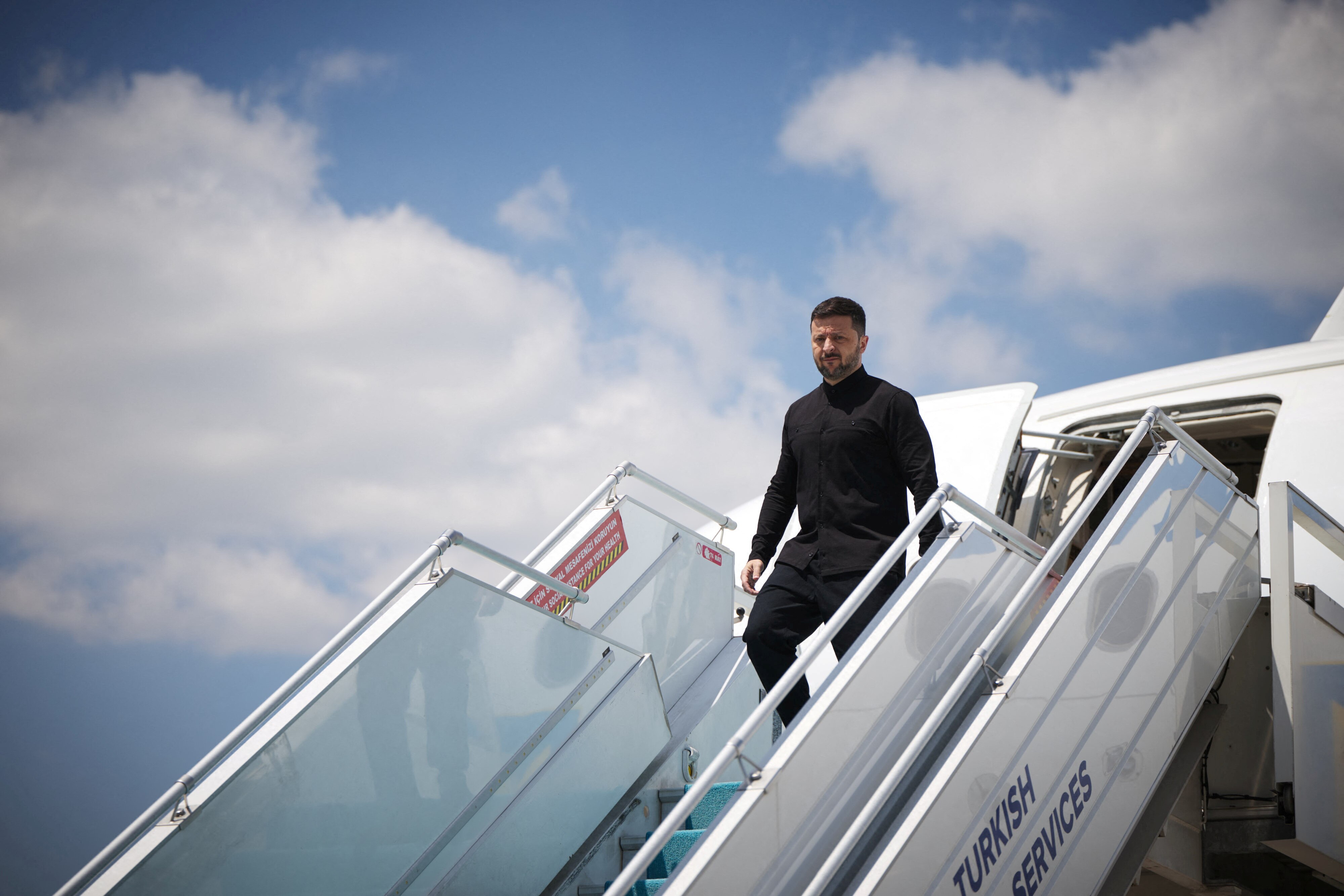 Zelenskky descends stairs from an aircraft