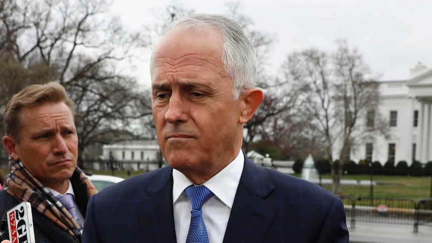 Malcolm Turnbull stands in front of a press pack.