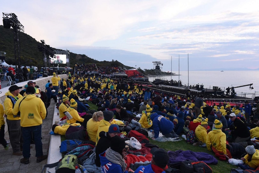 People wait at Anzac Cove at dusk