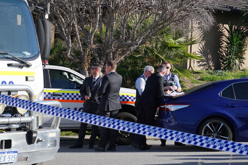 Police vehicles, officers and detectives on a road in suburban Perth with police tape in the foreground.