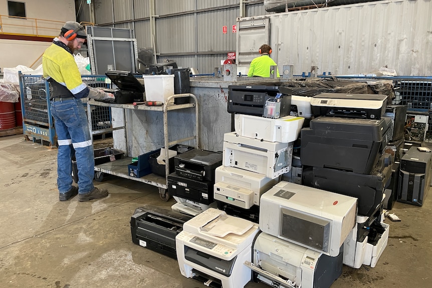 a worker dismantling printers in e-waste recycling facility 
