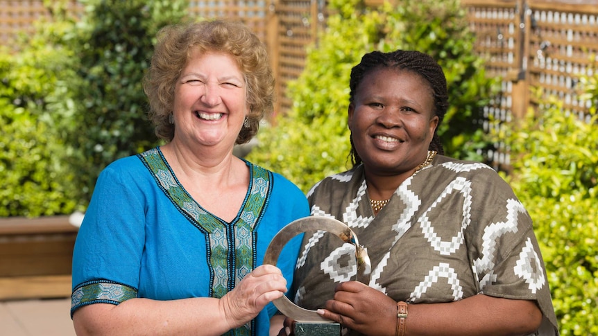 Liz McDaid and Makona Lekalakala stand together holding their trophy