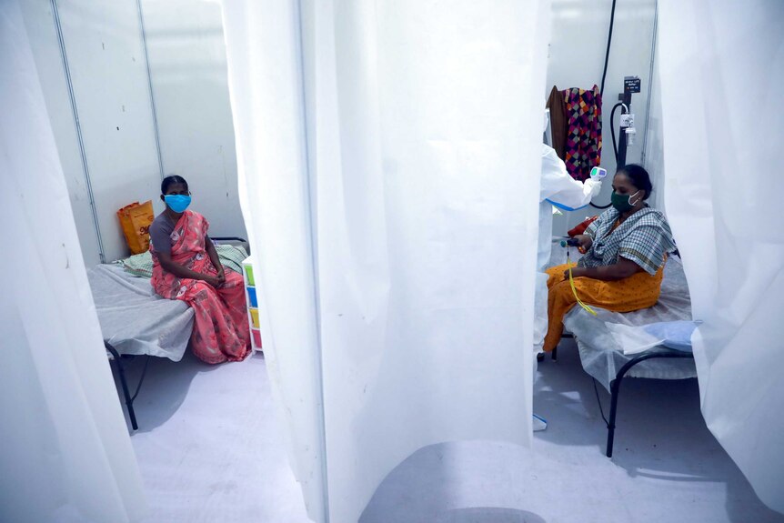 Two Indian women in hospital rooms separated by a white curtain