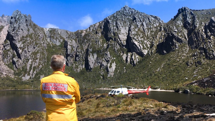 A firefighter stands next to a chopper at Lake Rhona