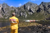 A firefighter stands next to a chopper at Lake Rhona