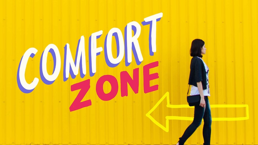 Woman walking against a yellow wall with the painted title 'comfort zone'.