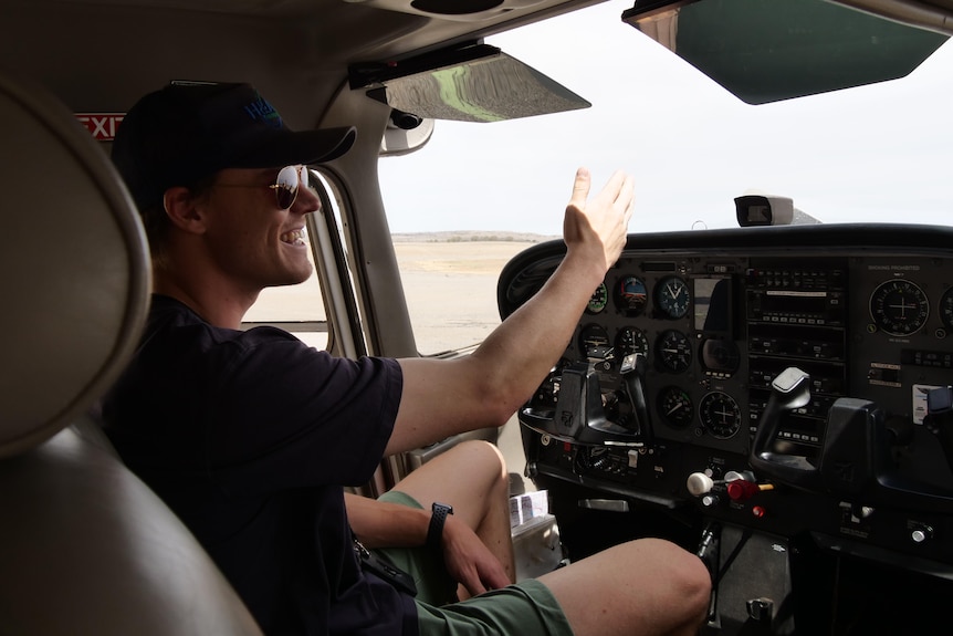 A man points towards the windshield from inside the cabin of a small plane.