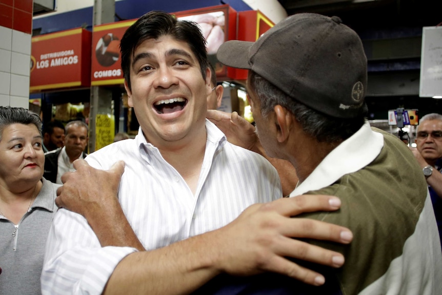 Carlos Quesada is seen greeting an older man.
