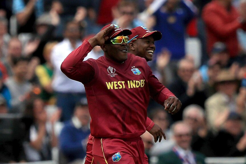 Sheldon Cottrell salutes with a teammate running behind him smiling