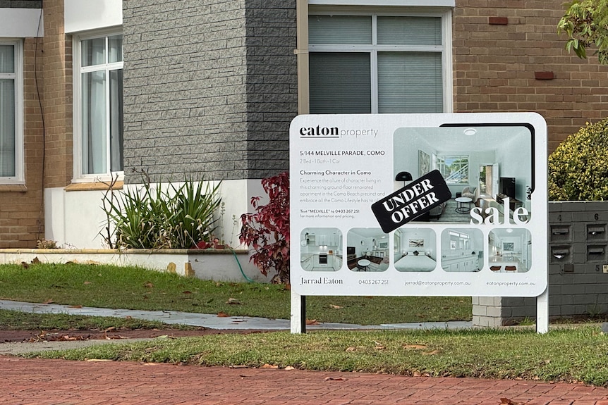 a white sign with "under offer' is standing infront of a block of units