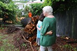 Woman hugs another woman standing in front of fallen tree trunk.