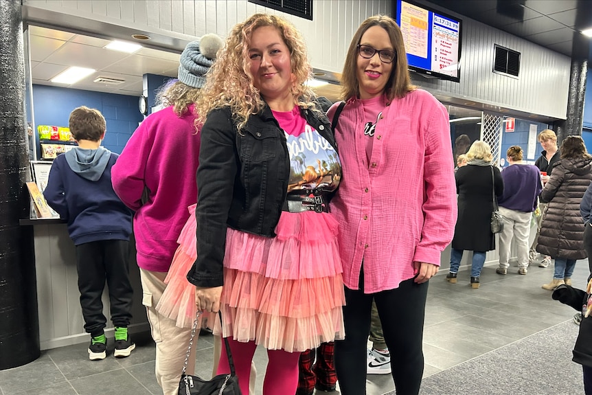 Two women wearing pink clothes smile at the camera.