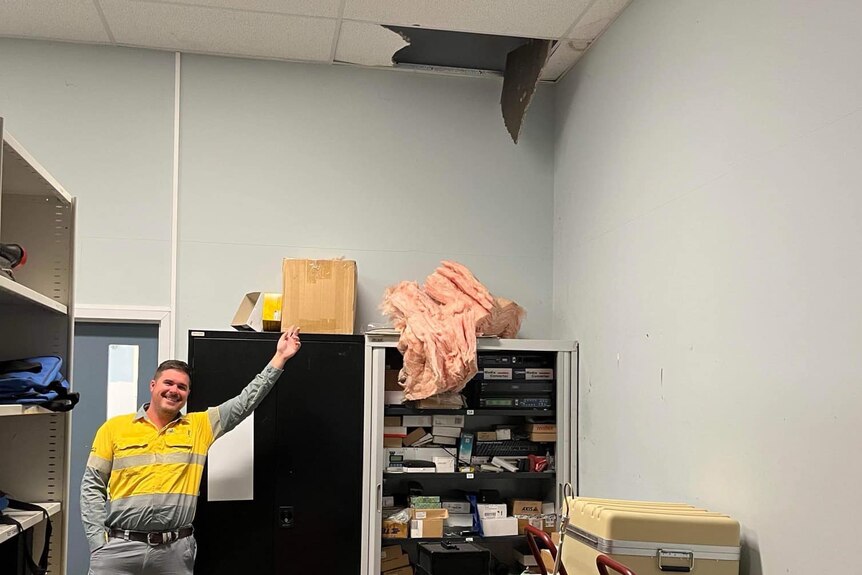 Man pointing to a hole in the ceiling, where the cat had been living