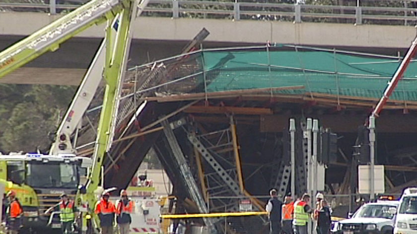 Crews stand at the site where a bridge collapsed over the Barton Highway
