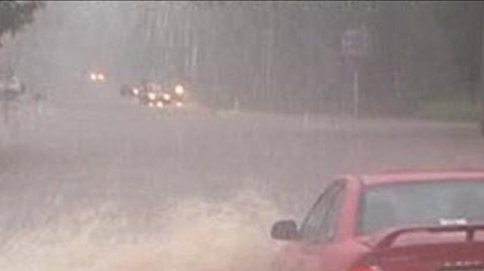 TV still of cars driving through floodwaters across a road on Qld's Sunshine Coast