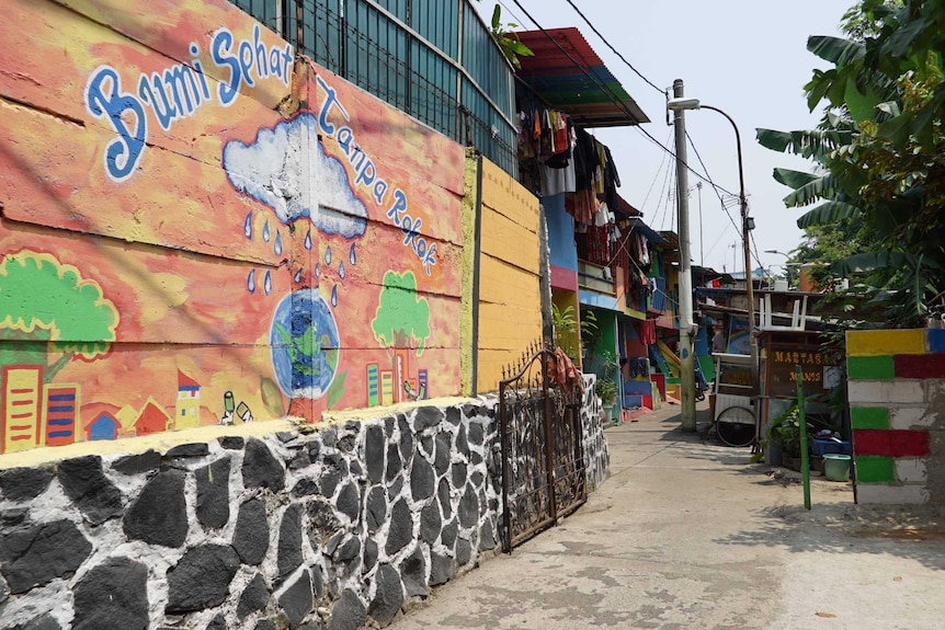 A colourful mural depicting a raincloud over planet Earth marks the entrance to a village in Jakarta