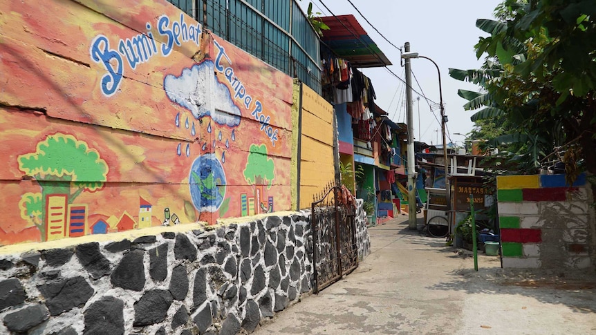 A colourful mural depicting a raincloud over planet Earth marks the entrance to a village in Jakarta