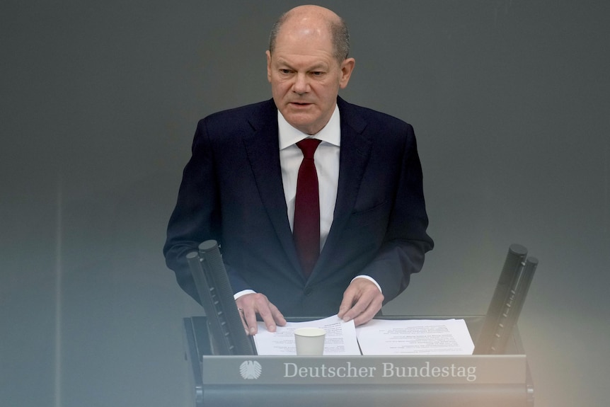 German Chancellor Olaf Scholz delivers a speech at a lectern.