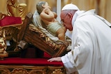 Pope Francis kisses a statue of baby Jesus as he leads the Christmas night Mass in Saint Peter's Basilica