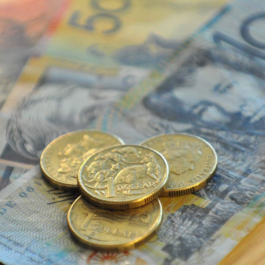 Australian dollar coins sit on banknotes.