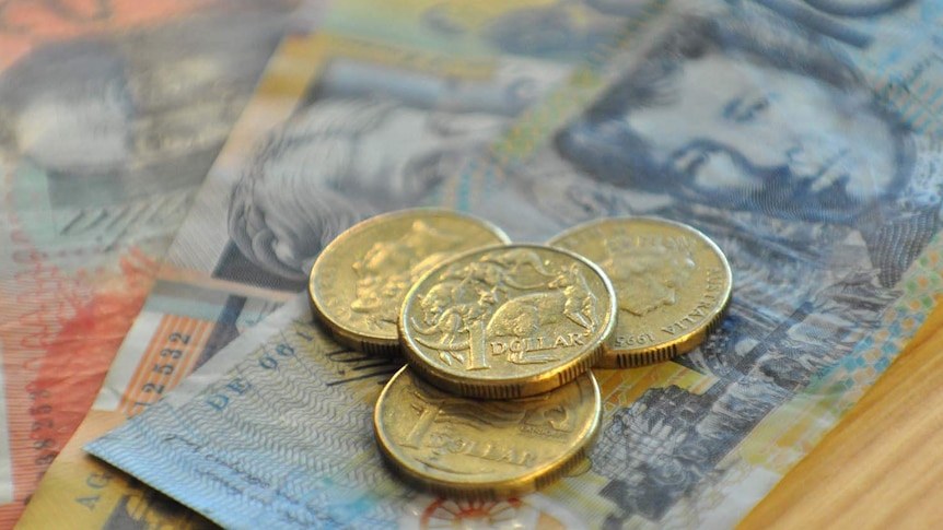 Australian dollar coins sit on banknotes.