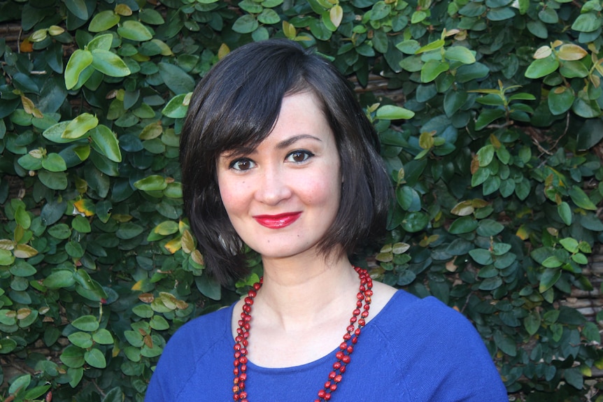 Ngila Bevan standing in front of green foliage