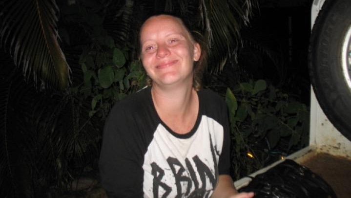 a woman in a black and white shirt smiles at the camera