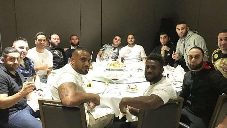 A group of men dine together at a large round table