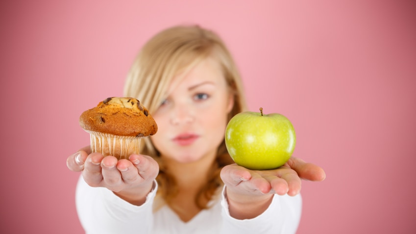 A woman holding an apple in one hand and a muffin in the other