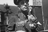 A black-and-white photo shows a British Army soldier holding a carrier pigeon during World War II.