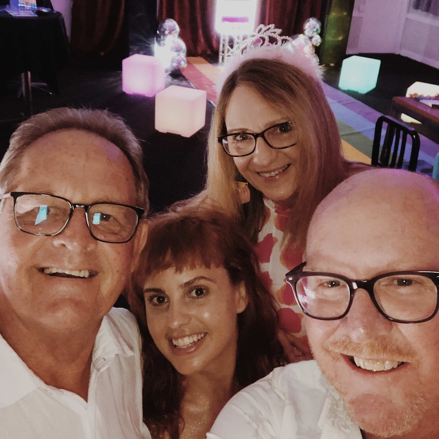 A family group bunched up at a bar, smiling.